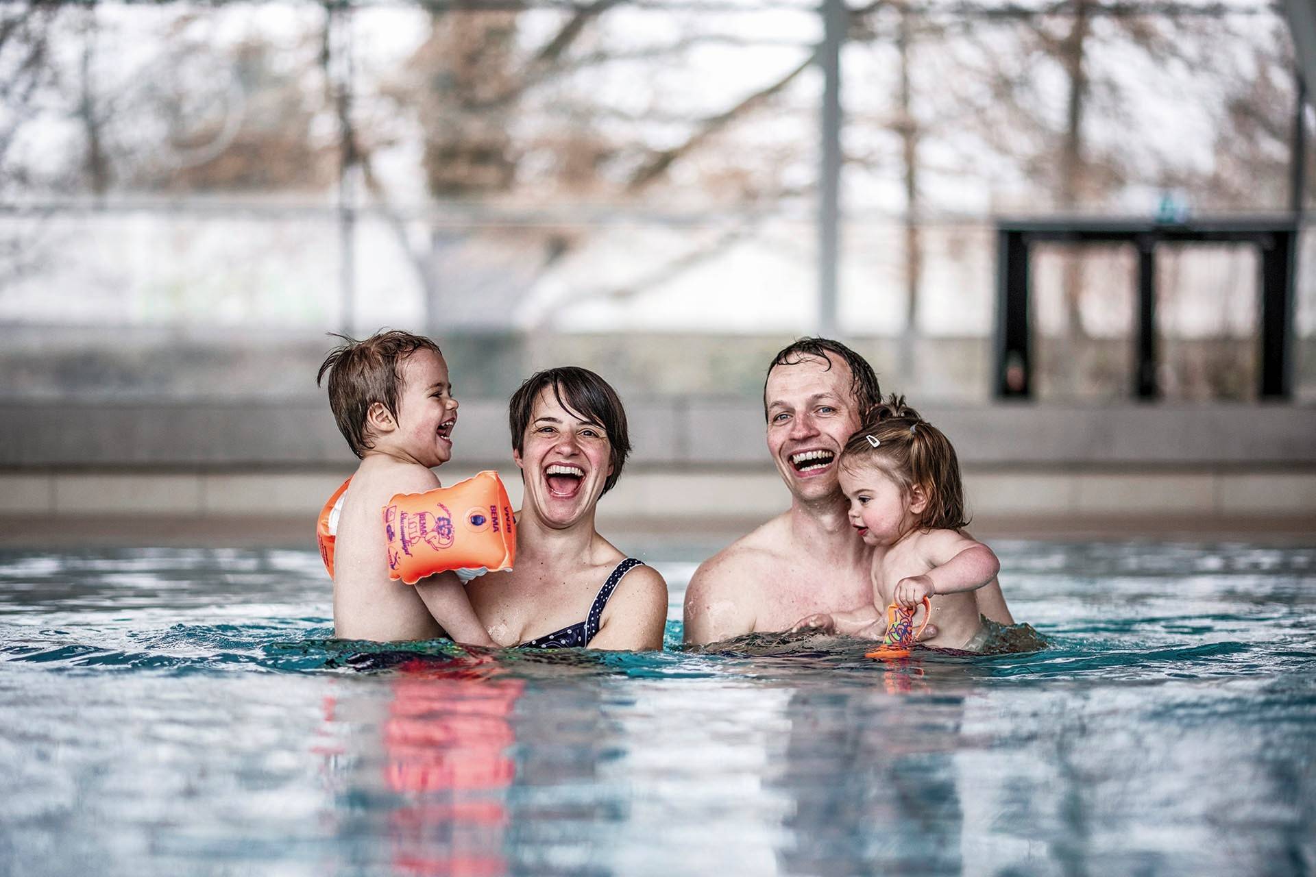 Freizeitbad Innenbereich, Eltern im Wasser mit ihren kleinen Kindern